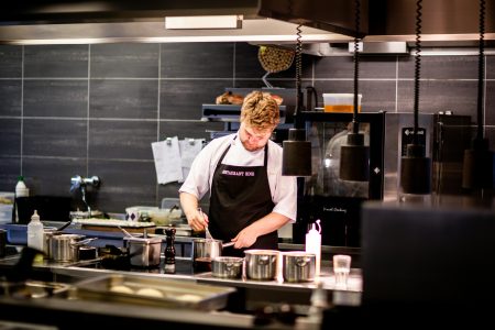Chef needed in Liverpool Chef preparing meal in a modern kitchen with various cookware.