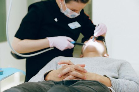 Patient receiving dental care from a dentist wearing gloves and mask in a clinic.