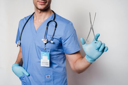Registered Nurse needed in Daventry (Visa Sponsorship Available) Healthcare worker in scrubs holding forceps, symbolizing medical professionalism.