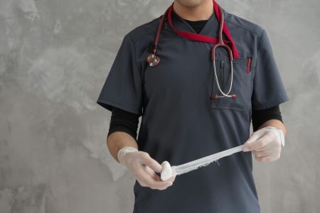 Healthcare worker preparing gauze bandage wearing stethoscope and gloves.
