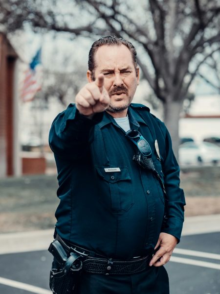 An angry police officer in uniform gestures outdoors, emphasizing law enforcement authority.