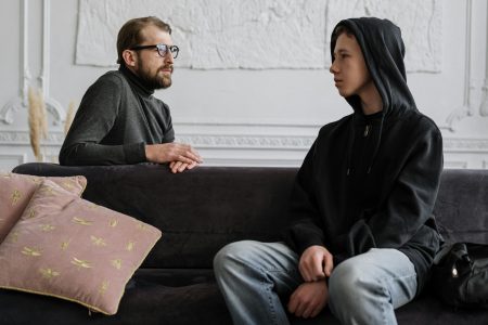 A psychologist and teenager engage in a counseling session in a cozy office setting.