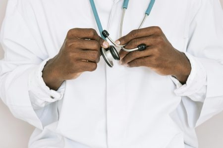 A professional doctor holding a stethoscope, focusing on hands and medical tools.