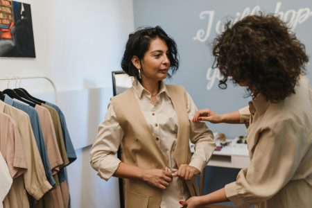 A fashion stylist helps a woman adjust her outfit in a trendy boutique.