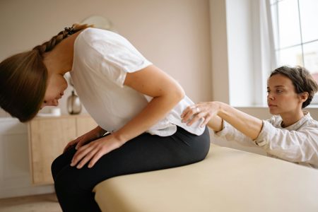 A therapist stretches a patient's back during a physical therapy session indoors.