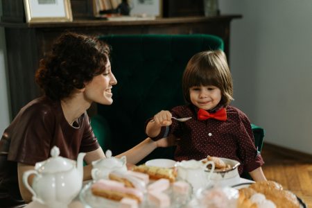 A woman and a young boy share a joyful afternoon tea indoors.