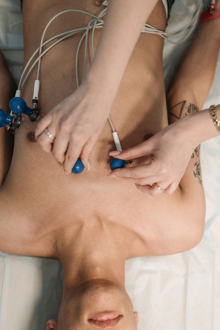 Cardiac Physiologist (Band 8A) needed in Chippenham (Visa Sponsorship Available) Close-up of a healthcare professional placing ECG electrodes on a patient's chest for heart monitoring.