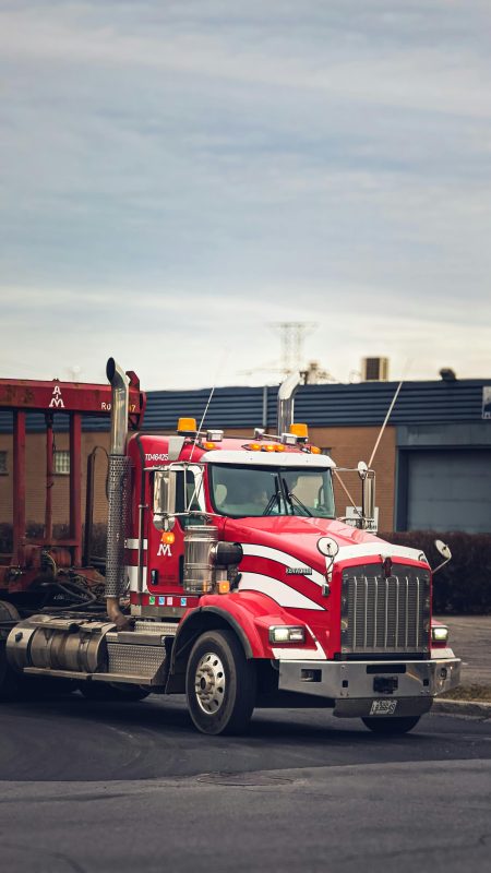 HGV Driver needed in Woolwich Vibrant red semi truck parked in an industrial area of Montreal, Canada.