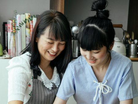 Domestic Assistant needed in Taunton Smiling ethic woman helping teen on kitchen near table while cooking and wearing aprons at home