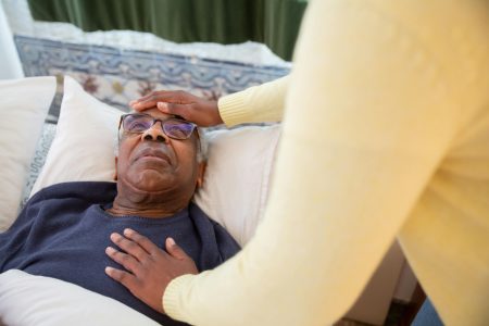 PCN Clinical Pharmacist needed in Goole (Remote) A caregiver attending to an elderly man in bed, providing comfort and support.