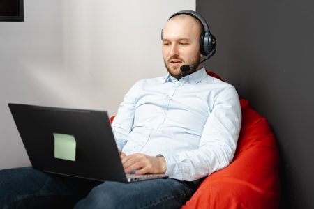 Call center agent working remotely on a laptop with headset and microphone for customer service.