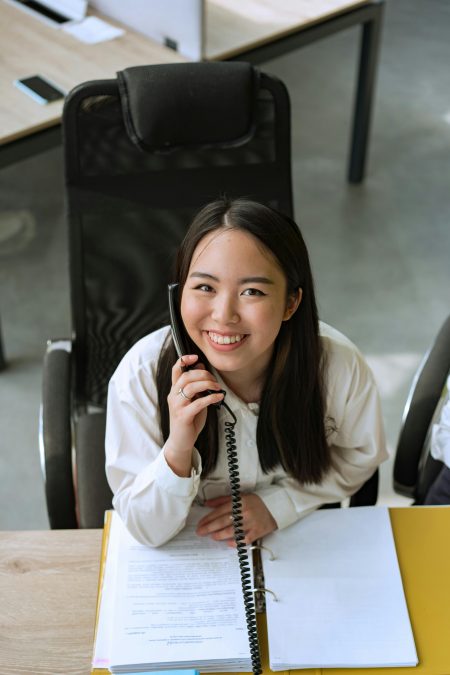 Reception Secretary needed in Walsall Smiling woman in office taking a phone call, conveying professionalism and friendliness.