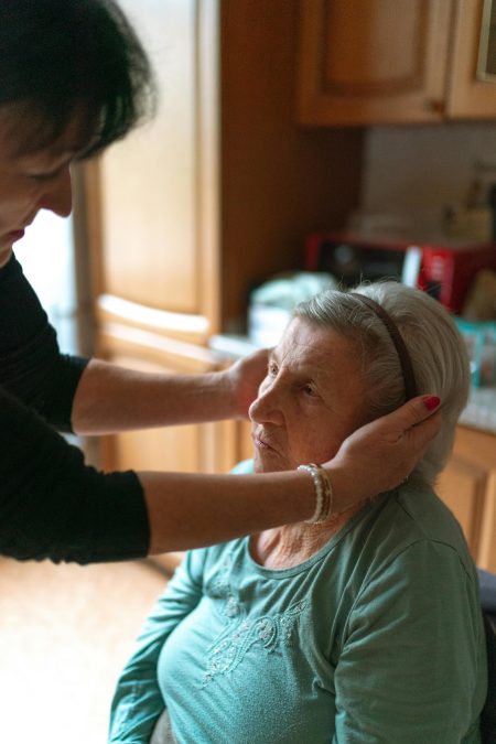 A senior woman receiving attentive home care assistance indoors, promoting comfort and support.