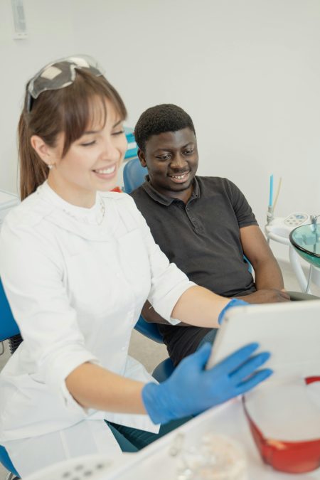 Dentist shows patient information on a tablet during a checkup at the clinic.