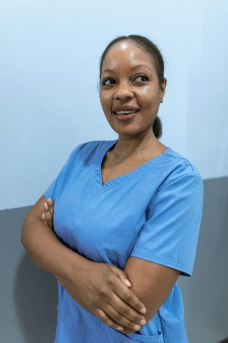 Smiling woman healthcare worker in blue scrubs standing confidently indoors.