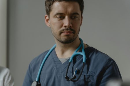 Close-up of a male healthcare worker with stethoscope in a clinical setting.