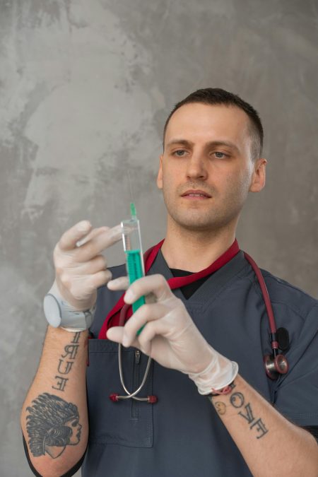 Healthcare professional in scrubs preparing a syringe indoors, focusing intently.