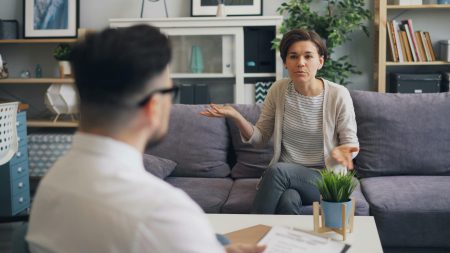 CAMHS Specialist Mental Health Practitioner needed in Nottingham (Visa Sponsorship Available) A woman consulting with a professional therapist in a modern office setting.