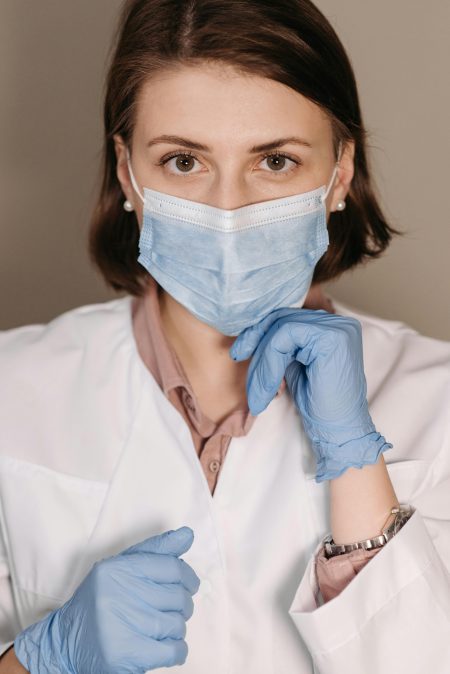 Health Protection Practitioner needed in Horsham/Ashford (Visa Sponsorship Available) Portrait of a female healthcare worker with face mask and gloves, ready for medical care.