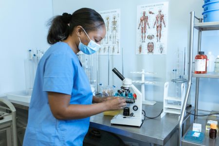 Associate Healthcare Scientist needed in Plymouth (Visa Sponsorship Available) Professional healthcare worker using a microscope in a lab, showcasing scientific research and analysis.