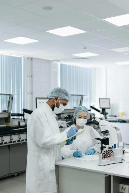 Researchers in protective gear working on a microscope in a laboratory, showcasing modern scientific research.