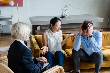 A couple having a therapy session with a psychologist in a modern office setting.