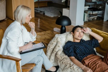 Psychologist listens attentively to a stressed young woman during therapy session.