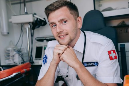 Portrait of a smiling paramedic inside an ambulance, representing healthcare and emergency services.