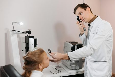 A medical professional examining a child's vision using specialized equipment.