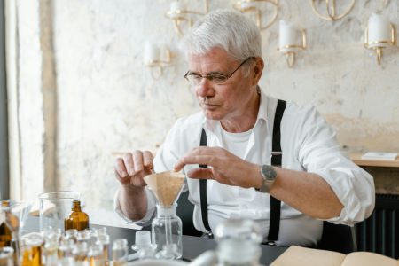 A senior scientist carefully prepares a liquid experiment at a laboratory table.