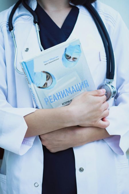 A doctor holds a reanimation handbook with a stethoscope, symbolizing expertise in emergency medicine.