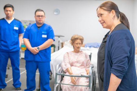 Nursing students and an instructor engage in a realistic clinical training using a medical mannequin.