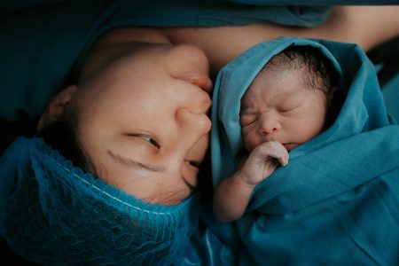 A touching image of a mother and her newborn baby wrapped in blue medical blankets.
