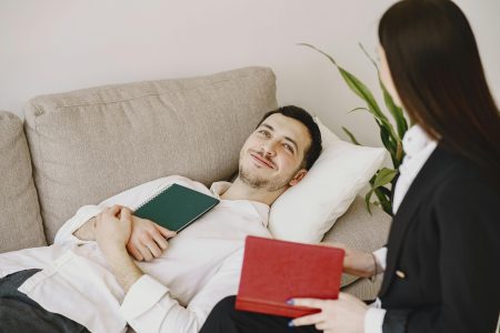 A relaxed patient lying on a couch during a therapy session with a professional therapist.