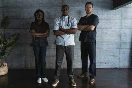 Confident medical professionals standing in hospital with arms crossed.