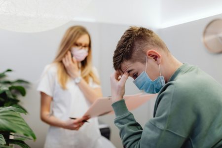 A worried patient discusses with a healthcare professional in a medical office setting.
