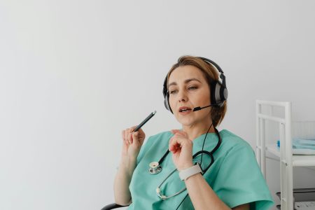 Doctor wearing headset and scrubs engages in an online consultation