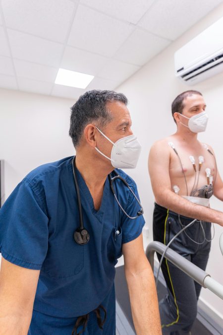 A doctor monitors a patient's cardiac stress test in a clinical setting, ensuring patient safety.