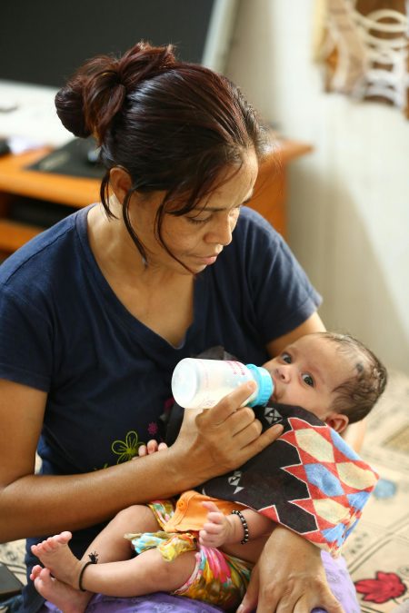 Mother tenderly feeds her baby with a bottle, showcasing love and care.